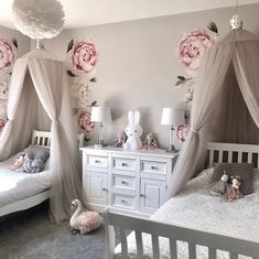 two white beds sitting next to each other in a room with pink flowers on the wall