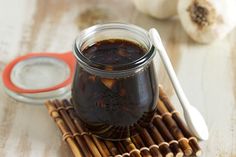 a glass jar filled with brown liquid next to chopsticks on top of a wooden table