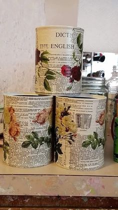 three tins are stacked on top of each other with flowers and leaves painted on them