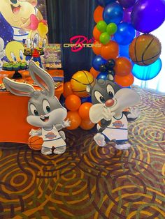 two cartoon rabbits standing next to each other in front of some balloons and basketballs