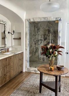 a bathroom with marble walls and flooring has a vase on the table in front of the shower