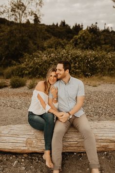 a man and woman sitting on a wooden bench in the middle of a dirt field