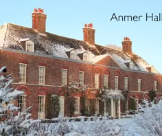 an old red brick building with snow on the ground and trees in front of it