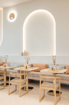 the interior of a restaurant with tables, chairs and couches in front of round windows