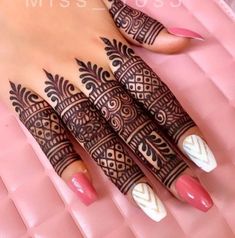 a woman's hand with henna tattoos on it and pink manicures