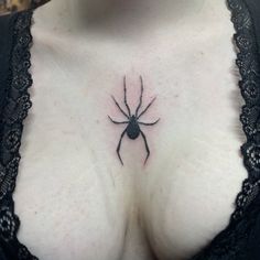 a close up of a woman's chest with a spider tattoo on her chest