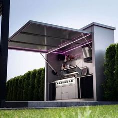 an outdoor kitchen is lit up with purple lights in the shade and surrounded by green grass