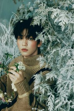 a young woman is holding flowers in her hands and posing for the camera, surrounded by snow - covered branches