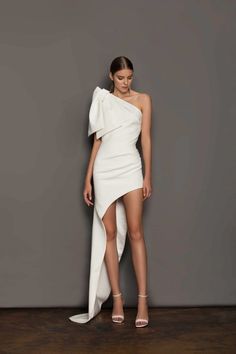 a model in a white one shoulder dress with high slits on the bottom and an asymmetrical neckline