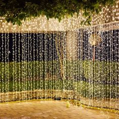 string lights hanging from the side of a building in front of a wooden floor and tree