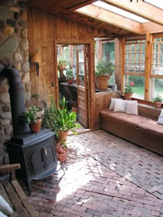 a living room filled with lots of furniture next to a brick floor covered in potted plants