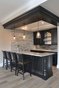 a kitchen with an island and bar stools next to it in front of a stone wall