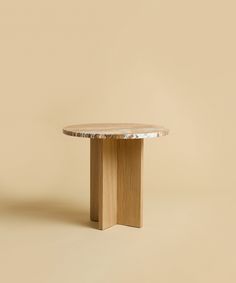 a wooden table with a marble top on a beige background in front of a wall