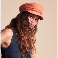 a woman with long hair wearing a red hat and denim overalls, posing for the camera