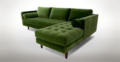 a blue velvet couch and ottoman with wooden legs in front of a white background,