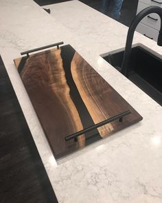 a wooden cutting board sitting on top of a kitchen counter next to a black faucet