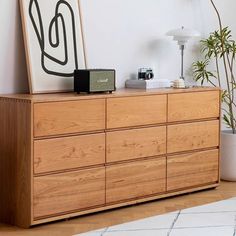 a wooden dresser sitting next to a plant in a living room