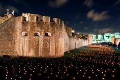 an image of a castle at night with lights on the ground and people walking around