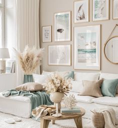 a living room filled with white furniture and pictures on the wall above it's coffee table