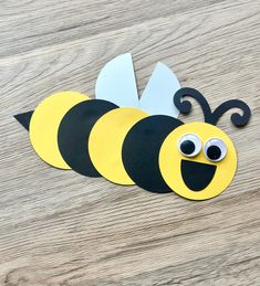 a paper cut out of a bee sitting on top of a wooden table