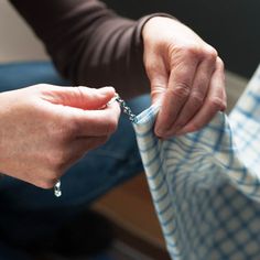 a person is sewing on a piece of cloth with a pair of scissors in their hands