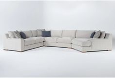 a large sectional couch with pillows on it's back and side ends, in front of a white background