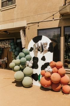 an outside display of balloons and decorations in front of a building with a cow on it