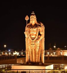 a large golden statue sitting on top of a lush green field