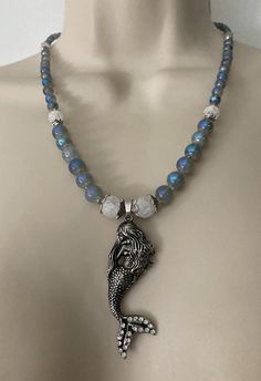 "This is a beautiful beaded mermaid pendant necklace.  It consists of various size Sapphire beads, frosted crackle white beads, steel plated mermaid pendant, silver plated spacers and tiny Czech glass spacer beads.  It is constructed of stainless steel jewelry wire and silver plated toggle clasp.  The  beads have a beautiful luster, the color of a beautiful sea.  It measures 20\". The necklace is shipped in a fabric gift bag and box.  Ideal for gift giving. I take pride in  my work, and customer satisfaction is very important to me.  If you have any questions or requests, please feel free to contact me." Silver Beaded Pendant Necklace With Lobster Clasp, Silver Crystal Beaded Necklace With Gemstone Beads, Silver Beaded Pendant Crystal Necklace, Mermaid Pendant Necklace, Beaded Mermaid, Fabric Gift Bag, Sapphire Beads, Bijoux Fil Aluminium, Mermaid Pendant