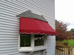 a red awning on the side of a white house