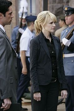 two men and a woman are standing in front of other uniformed people on the street