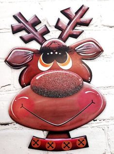 a red and black metal reindeer head mounted on a white brick wall with crosses around it's eyes