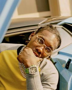 a woman wearing glasses leaning on the door of a car