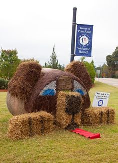 there is a fake bear made out of hay in the grass with a sign on it