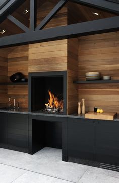 a kitchen with a fire place in the center and wooden walls on both sides, along with black cabinets