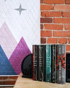 the books are lined up next to each other near a wall with a quilt on it