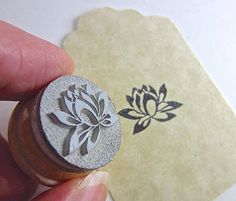 a hand holding a stamp with a flower on it