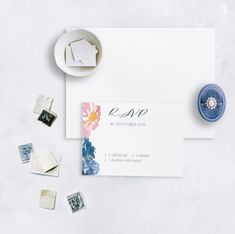 the wedding stationery is laid out next to stamps and a ring on a plate