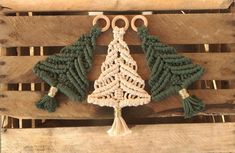 a crocheted christmas tree on a wooden pallet with crescents and tassels