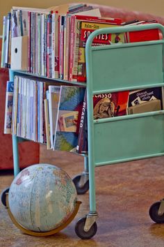 a blue cart with books and a ball on the floor