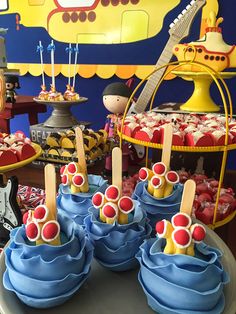 a table topped with cupcakes covered in blue frosting and candy toppings