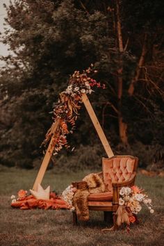 an old chair is set up with flowers and greenery on the back for a wedding ceremony