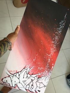 someone holding up a piece of art that has been painted with red and white paint