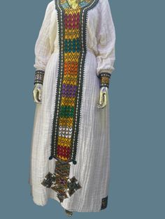 Fetel dress from axum Tigray Ethiopia. It's hand woven from an organic cotton and hand embroidered. The dress is very graceful and can be worn for a wedding, christening and holidays.  Please add your measurements when placing your order.  Since it's hand embroidered it takes about a month to make unless we have a ready-made one in your size delivery might take 4-6 weeks. White Dresses With Weaving Work For Traditional Ceremonies, White Folk Dress With Weaving Work, Long Sleeve Dress With Multicolor Embroidery And Woven Motifs, Folk Style Dresses With Weaving Work For Traditional Ceremonies, Traditional White Handwoven Dress, White Embroidered Dress For Traditional Ceremonies, White Folk Dress With Woven Motifs, White Long-sleeve Kaftan With Woven Motifs, White Long Sleeve Kaftan With Woven Motifs