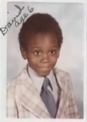 a young boy in a suit and tie posing for a photo with his name on it