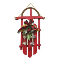 a red wooden sled with wreaths and bells hanging from it's side