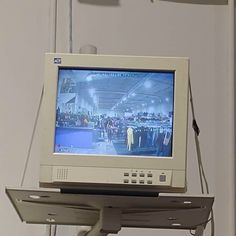 an old computer monitor sitting on top of a metal shelf in front of a white wall