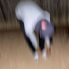 blurry photograph of two people on skateboards in front of a wooden wall and floor