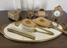 a table topped with gold and white items on top of a wooden table next to a clock