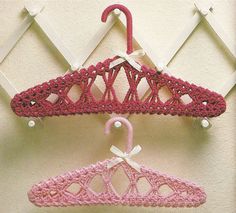 two crocheted hangers are hanging on the wall next to each other, one pink and one white